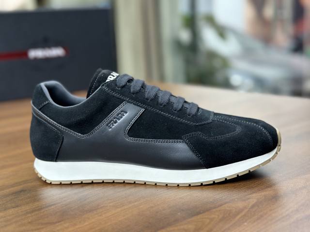 prada 新款男士绒面皮革运动鞋 这款运动鞋采用绒面牛皮革打造，鞋侧涂珐琅三角形徽标焕发出新的运动活力，在鞋侧引人注目，鞋舌饰有prada Milano丝网印