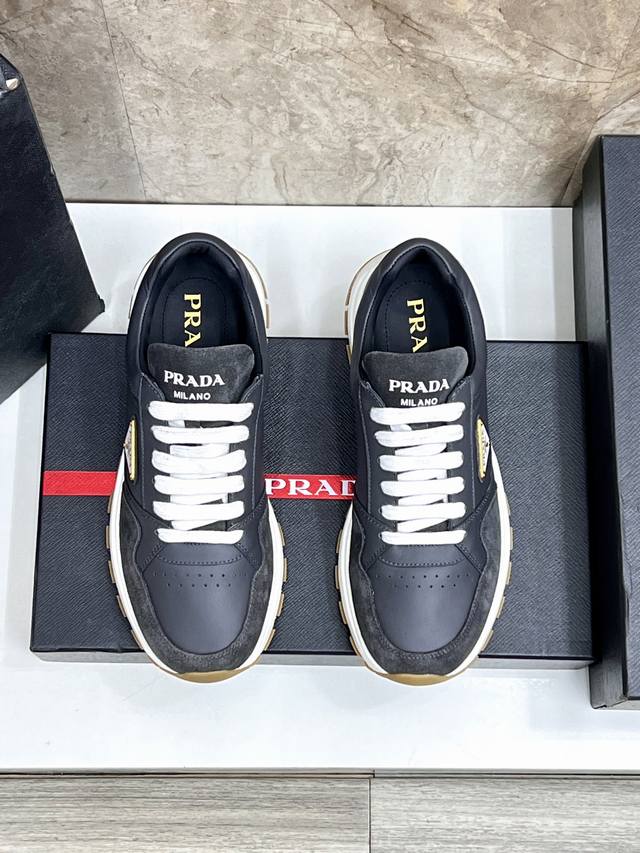 Prada 普拉达 男士新款厚底拼接运动鞋，这款厚底运动鞋采用牛皮制成，搭配加厚橡胶发泡中底拼接前后包裹的细纹橡胶鞋底，饰有品牌字母立体标识，鞋舌饰有经典P家红
