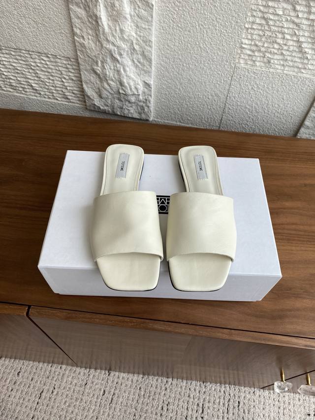 顶级版本: Toteme 2025 夏季新品 平底 一字拖 绷带式拖鞋 这款Toteme 拖鞋以柔软的牛皮制成，采用简约的绷带式鞋面计。配有皮革鞋垫及鞋底，后跟