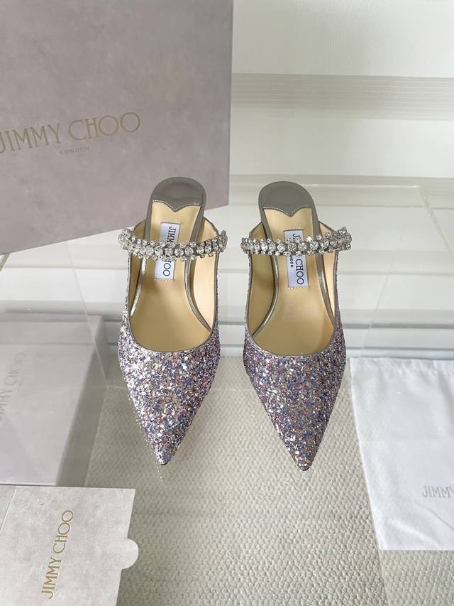 Jimmy Choo Bing 系列闪粉面料标志款穆勒鞋，摩登时尚。优美一脚蹬设计，配以6.5厘米小细跟，个性别致。足弓饰带精心点缀水晶，隐隐散发魅力，搭配小黑