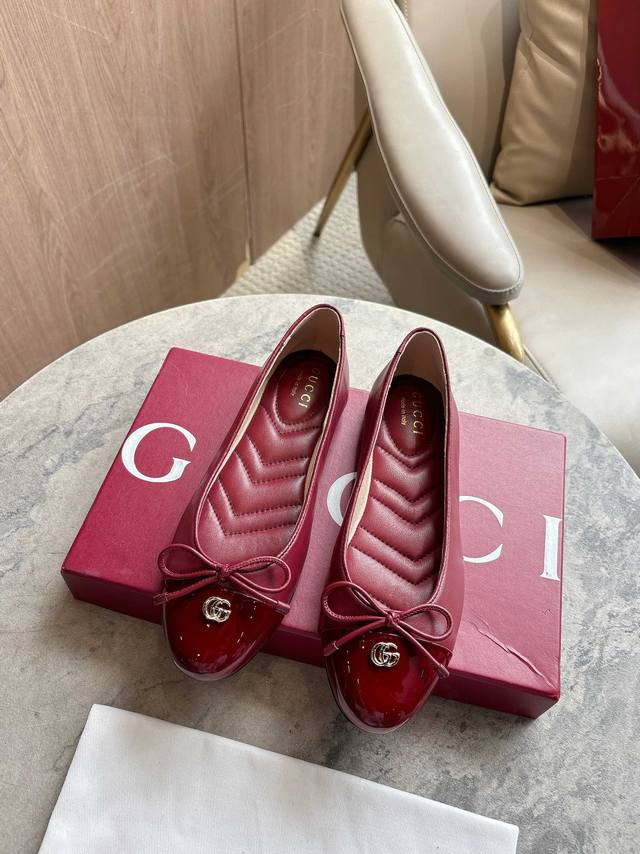 1054-1 酒红 35-42 这款平底芭蕾舞鞋选用光面皮革制作，配以漆皮鞋头，尽显优雅隽永格调。精巧蝴蝶结流露女性气质，浅金色调双G配件低调呼应品牌高辨识度标