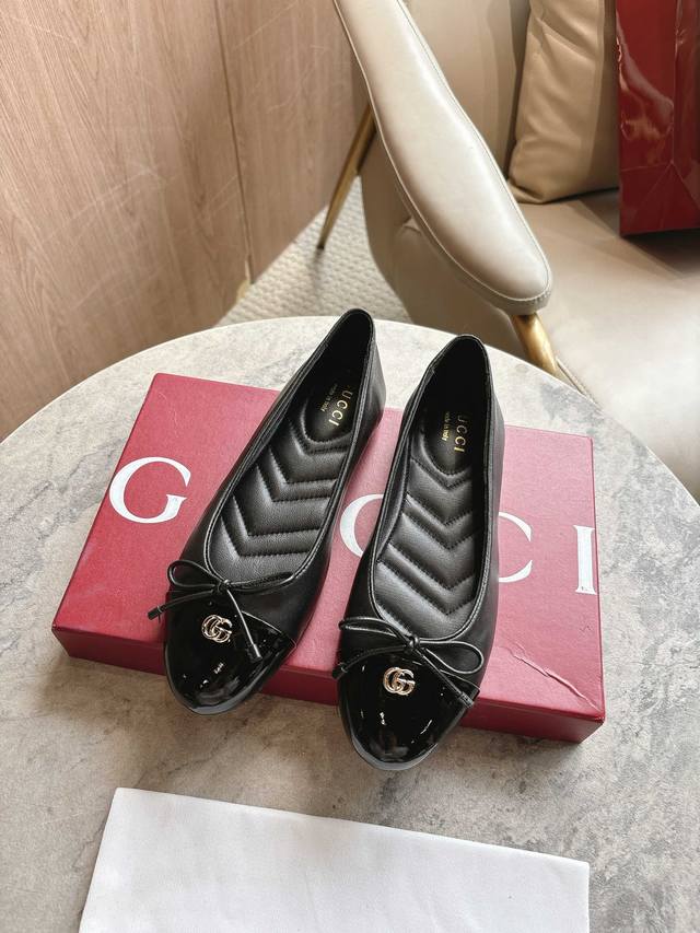 1054-1 黑 35-42 这款平底芭蕾舞鞋选用光面皮革制作，配以漆皮鞋头，尽显优雅隽永格调。精巧蝴蝶结流露女性气质，浅金色调双G配件低调呼应品牌高辨识度标识