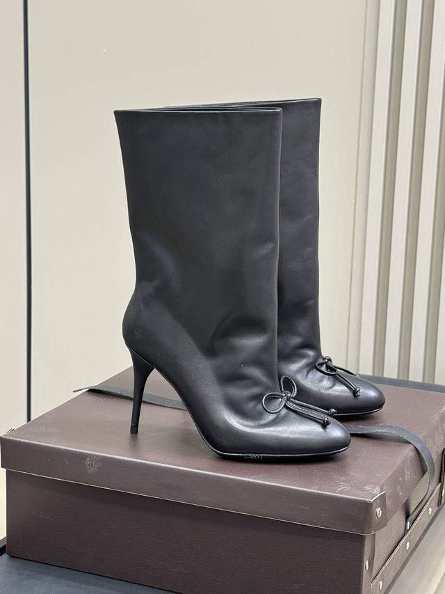顶级品质 Alaia｜易梦玲同款高跟短靴 该款黑色小牛皮高跟短靴，正面点缀装饰蝴蝶结，搭配90毫米鞋跟与22厘米靴筒；时尚百搭造型，凸显女性独特魅力！ Size