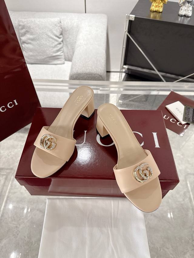 Gucci 2025春夏新款双G钻扣露趾高跟凉拖鞋每个细节皆经过精心细致打造，巧妙运用圆头和粗跟等设计元素演绎时尚复古风范。典藏的双G镶钻扣细节令人联想起品牌的