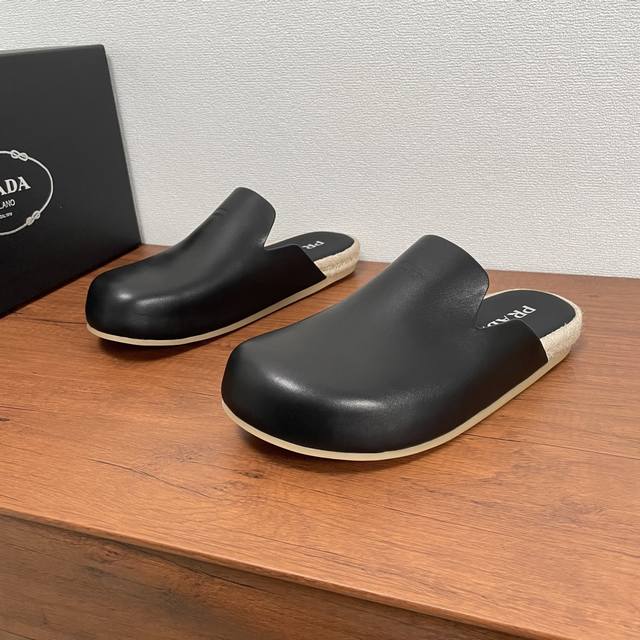 Prada 新款男士穆勒鞋时尚半拖 这款时尚休闲穆勒鞋巧妙融合质感绒面牛皮革和小牛皮，精致质感，正面饰以Prada Milano字母压纹徽标，编织绳内底搭配牛皮