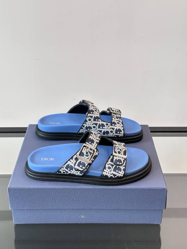 Dior Aqua 男士凉鞋拖鞋。展现 Dior 高订风格设计。迪奥灰绒面革饰带点缀以铝质 Dior 搭扣提升格调。搭配舒适的同色调凹口鞋底，可与短裤或牛仔裤轻