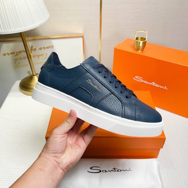 Santoni 圣东尼 这是一款男士低帮运动鞋，由意大利制造。 材质与构造：采用荔枝纹皮革制作，未加内衬且解 构设计，呈现简约风格。 颜色与细节：鞋身为兰色，鞋
