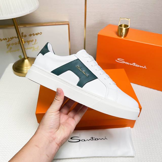 Santoni 圣东尼 这是一款男士低帮运动鞋，采用皮革材质，颜色 为白色和橙色，设计细节精致且富有特色。 材质与颜色：该鞋采用皮革制作，主体颜色为 白色和绿色