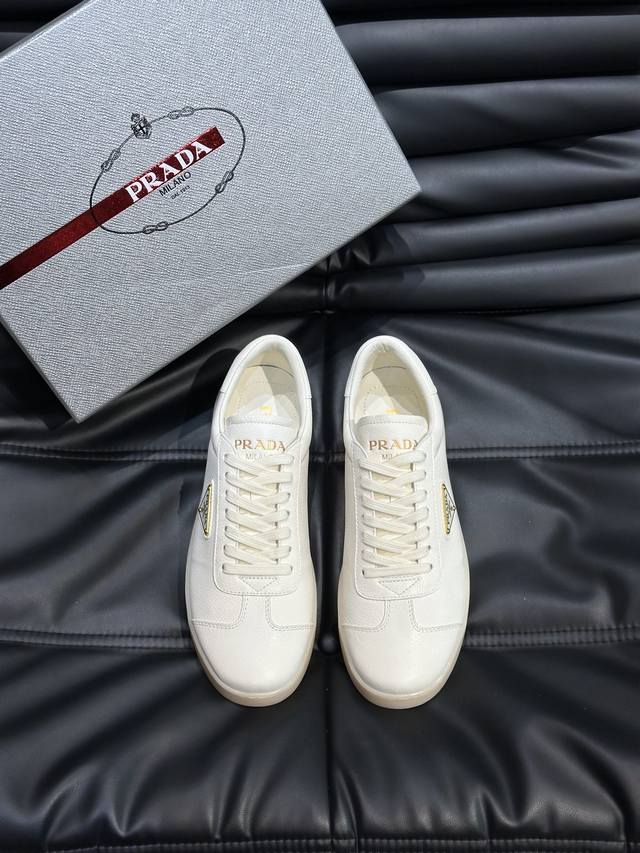 Prad* 普拉*新品男士高端运动鞋，这款运动鞋时尚百搭，简洁现代，融合运动风格和精致细节。选用皮革材质打造，搭配橡胶鞋底，鞋舌压印字母徽标，标志性的涂珐琅三角