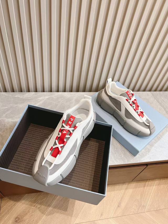 Prada 普拉达男士系带皮革休闲运动鞋，鞋面牛皮拼接透气网面打造 柔软舒适透气 鞋舌装饰Prada品牌字母标识 橡胶厚底与红标鞋舌相呼应 款式时尚大方 细节精