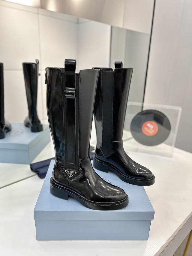 工厂P价 普拉达短靴 秋冬新款Prada普拉达三角标短筒切尔西 这款鞋履配有鲜明的圆形鞋头，橡胶厚底为经典乐福鞋注入现代外观，涂珐琅金属徽标装饰彰显品牌格调。惯