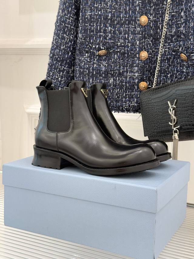 厂价 Prada 普拉达经典角标切尔西粗跟短靴 当切尔西靴的经典基因遇上标志性美学 这双短靴便成了秋冬穿搭的风格锚点 将品牌的设计哲学藏于步履之间。 而鞋身的灵