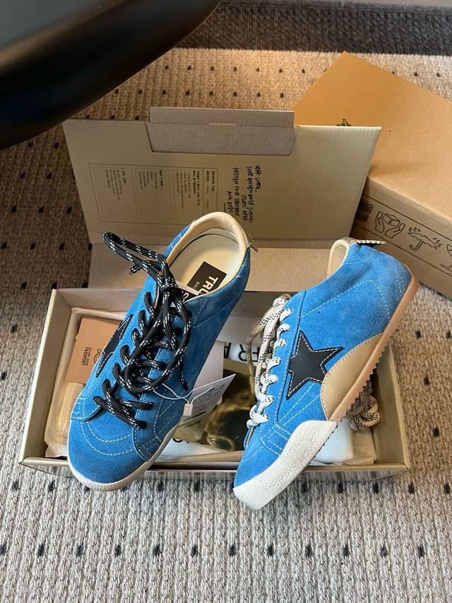 Ggdb Golden Goos* 25Ss做旧星星休闲板鞋 采用复古做旧工艺，蓝色麂皮材质呈现出自然的磨损质感，鞋身侧面的星形装饰增添辨识度，搭配黑白两色的鞋