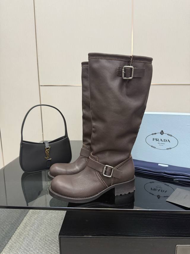 厂价 prada 普拉达25Wf秋冬新品皮带扣 复古粗跟长靴 经典的皮带扣设计 如同一把时光钥匙 打开复古与摩登交融的大门。 金属扣的光泽与皮革的质感相互映衬