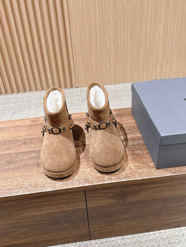 Balenciaga 巴黎世家秋冬铆钉皮带扣雪地靴 融合街头酷感与冬日保暖属性，鞋面采用麂皮材质，搭配金属铆钉装饰的皮带扣，打破传统雪地靴的“软萌”印象，增添叛