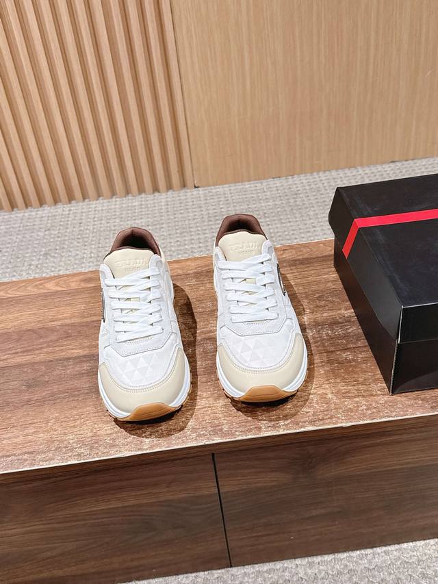 prada 普拉达新款男士厚底皮拼布运动休闲鞋 这款皮革运动鞋采用小牛皮拼接科技织物鞋面，布面带几何纹理，糅合优雅风范与创新设计。外侧饰以涂珐琅金属三角形徽标，