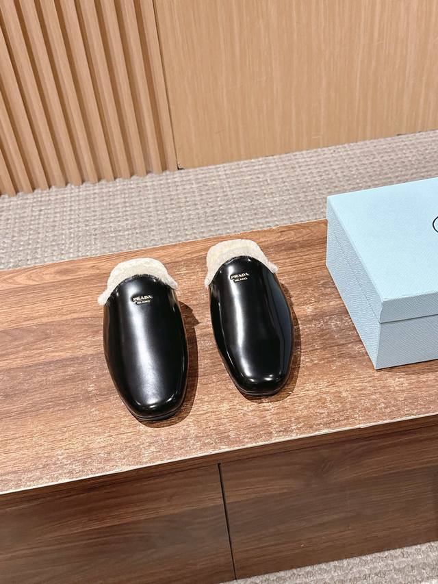 prada 普拉达秋冬新款毛绒穆勒鞋 融合了奢华质感与舒适休闲感，鞋面采用高级皮革 麂皮材质，鞋口处的毛绒设计既增添了温暖的视觉效果，又提升了穿着的舒适体验，鞋