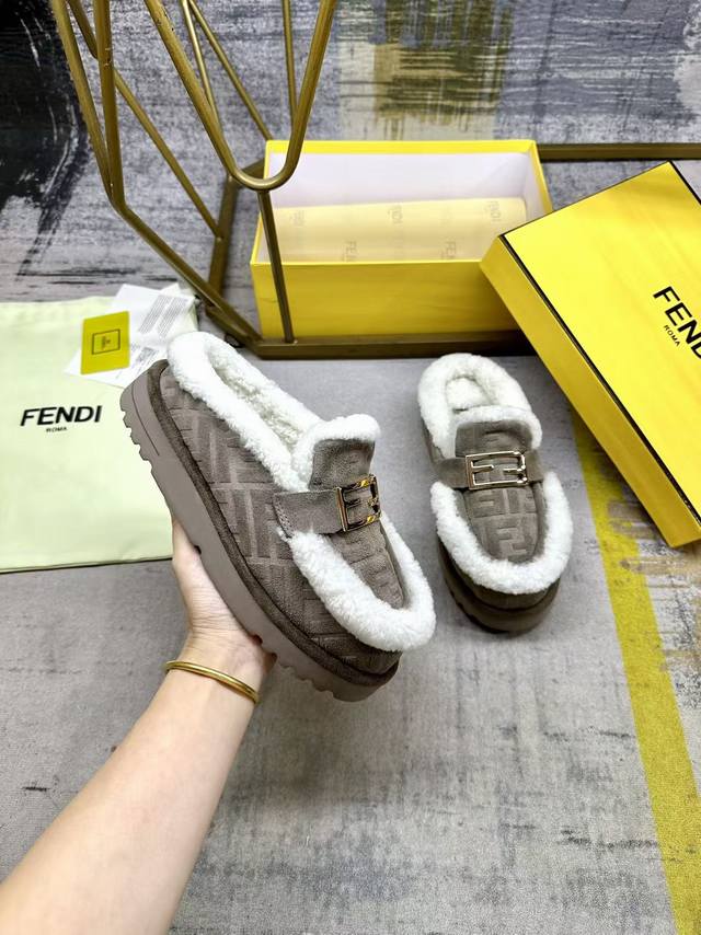 Fendi最新休闲圆头平底半拖鞋。采用灰色绒面材质饰有同色系凸纹Ff图案。白色羊卷毛内衬和饰边。饰有金色饰面金属Baguette配饰。厚实的同色防滑底，鞋跟Fe
