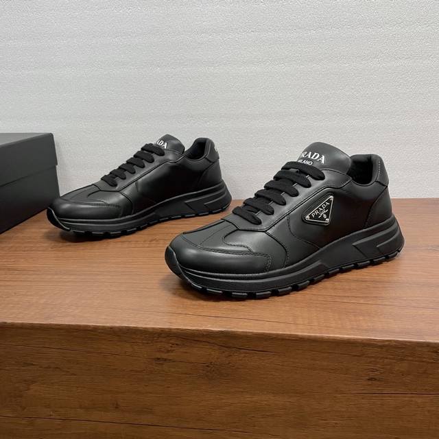 prada prax系列男士休闲运动鞋 这款prax运动鞋将风格与舒适融为一体，独特的运动设计由精致的材质和细节定义。采用进口小牛皮面打造，时尚休闲百搭，外侧饰