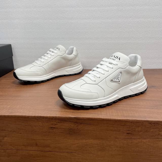 prada prax系列男士休闲运动鞋 这款prax运动鞋将风格与舒适融为一体，独特的运动设计由精致的材质和细节定义。采用进口小牛皮面打造，时尚休闲百搭，外侧饰