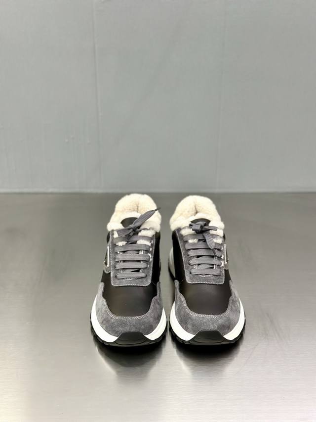 prada 普拉达 男士新款羊毛运动鞋 这款运动鞋呈现现代版型，以利落线条与流畅细节重新演绎品牌典藏款型。鞋履采用小牛皮革和科技织物打造，外侧饰有三角金属徽标，