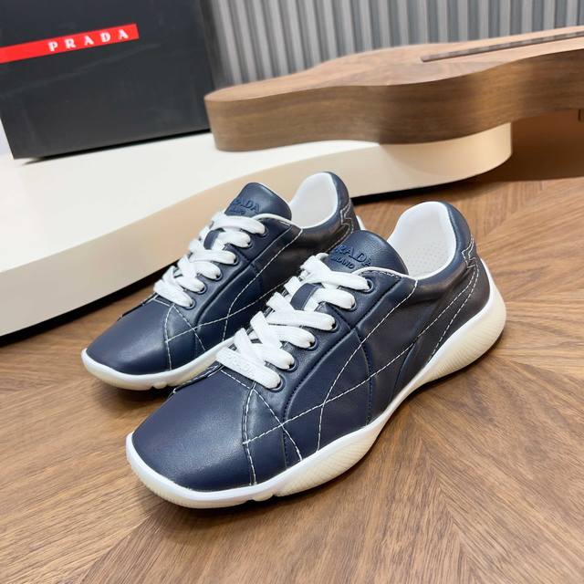 prada 新款男士拼接休闲运动鞋 这款运动鞋以精湛的缝线工艺勾勒出别具一格的几何纹理，当代风格线条与细节重新演绎经典的运动风格。采用超柔超韧羊皮鞋面，内里垫脚