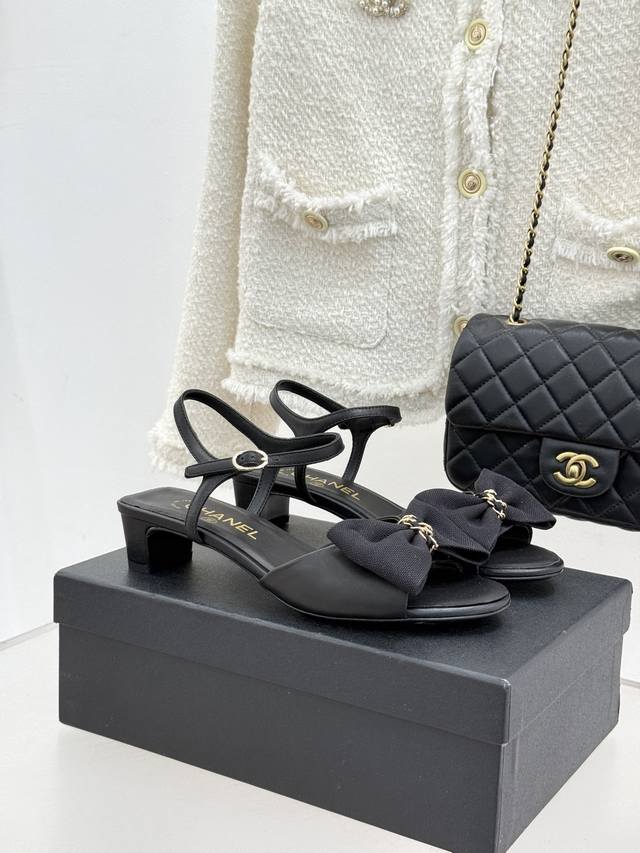 厂价 Chane*｜小香26C新品链条蝴蝶结 粗跟凉鞋 这款凉鞋以经典符号重构摩登美学 让每一步都成为优雅宣言。 当粗跟的稳愈邂逅蝴蝶结的柔 当金属链条的锋芒碰