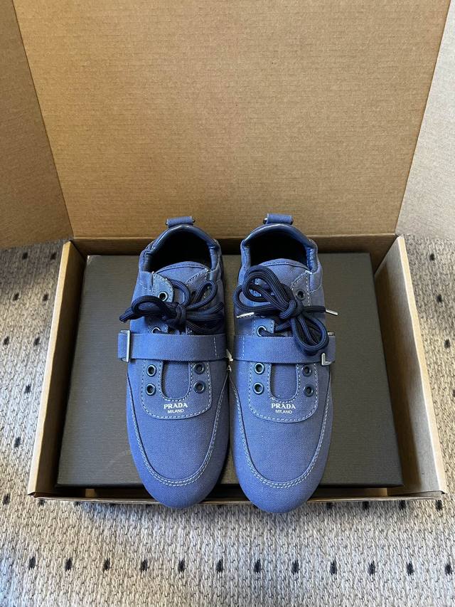prad*复古绑带平底休闲鞋阿甘鞋 鞋面采用帆布质感的面料，质感细腻，结合系带与魔术贴搭扣双重固定设计，兼具实用性与设计感；鞋型为低帮平底，线条简约流畅，偏向复